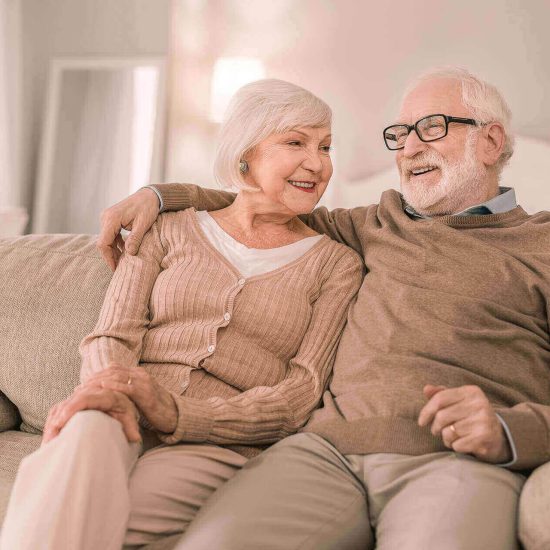 Two older adults relaxing together on a sofa