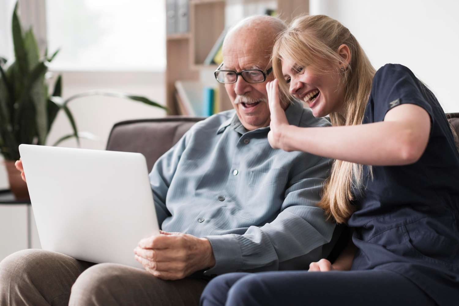A senior man and a caregiver laughing together at home